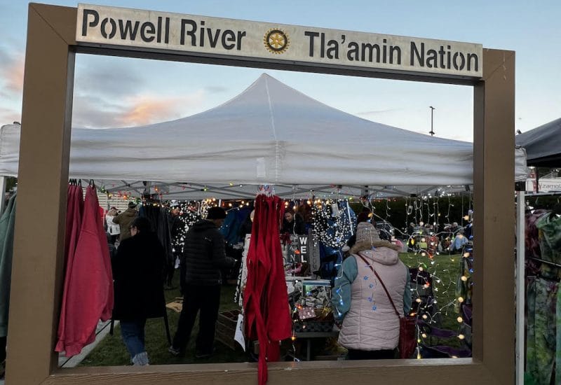 A sign above festively decorated vending tents reads "Powell River * Tla'amin Nation"