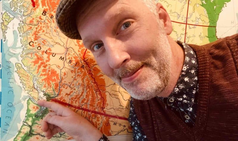 A white man with a grey beard points at Vancouver Island on a map.